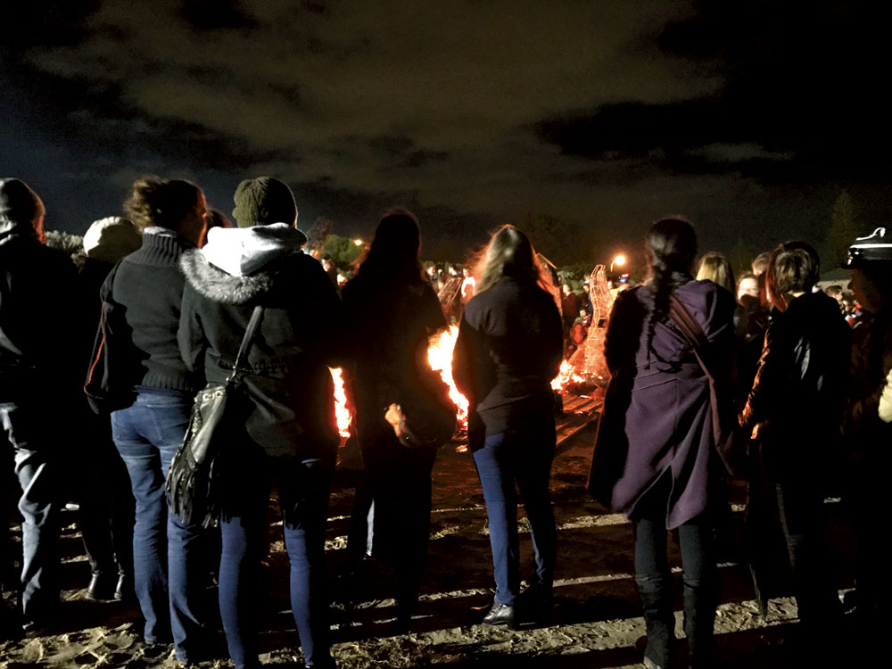 People standing around a fire at night