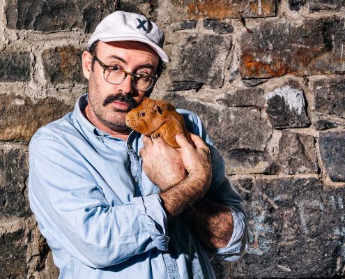 Sam Simmons holding a ginger hamster