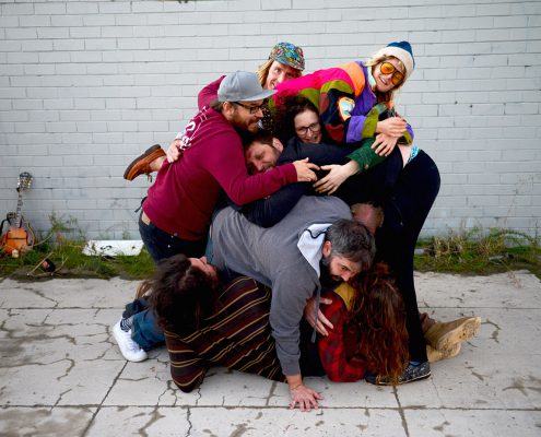 Band member pilled up on the ground on top of each other, horsing around