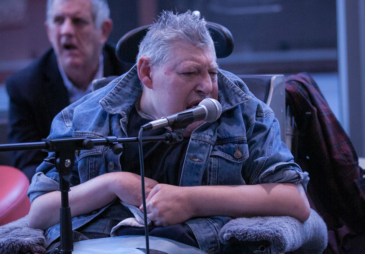 Man in a wheelchair talking at a microphone