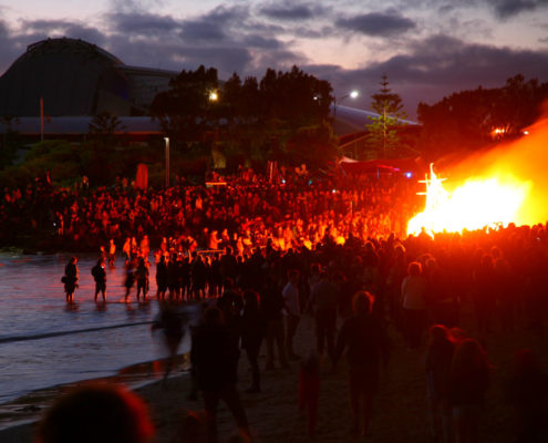 Crowd at twilight at Bathers Beach watching a ship-shaped structure burn