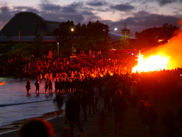 Crowd at twilight at Bathers Beach watching a ship-shaped structure burn